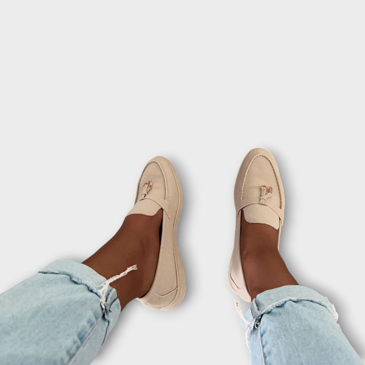 A woman wearing minimal slip-on loafers, styled for an easy everyday look.
