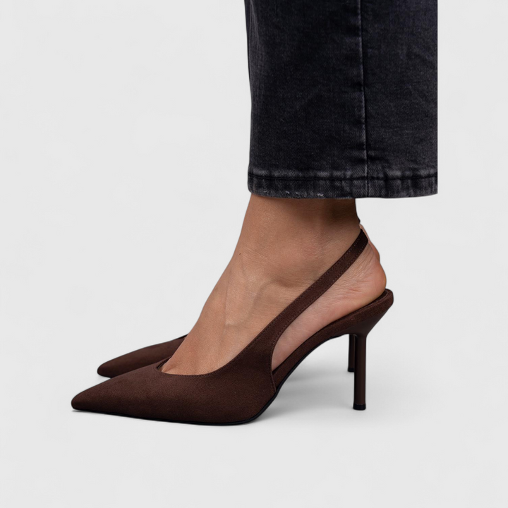 A woman wearing beige pointed slingback stilettos with a slim high heel.
