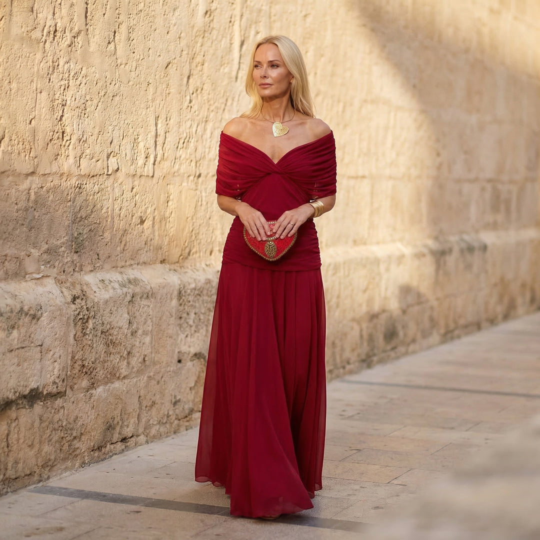 A woman wearing an elegant flowing red dress at an evening occasion.
