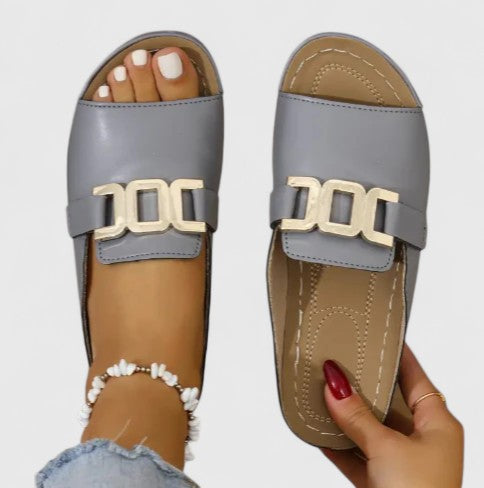 A woman wearing white comfort slides with a golden front trim and a cushioned sole.