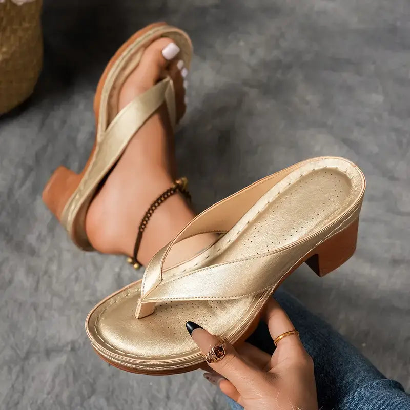 A woman wearing gold block heel sandals with a toe-post strap at an evening event.