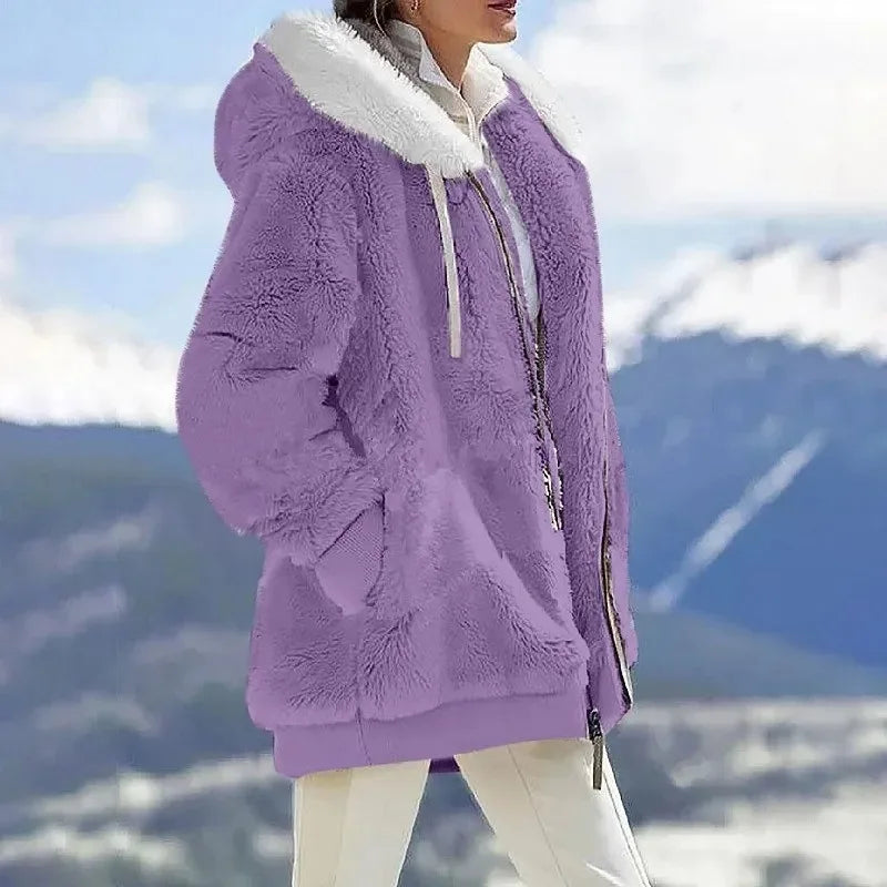 A woman wearing a plush oversized hooded zip jacket in blue and cream colour-block panels.