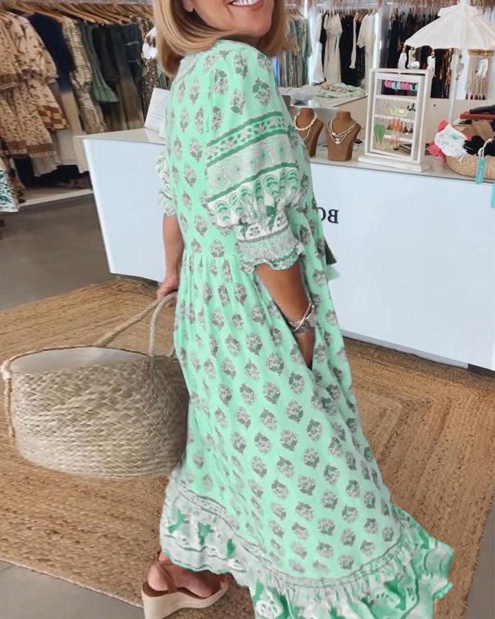 A woman wearing the Crystal boho beach dress with a flowing skirt, walking along the seaside.
