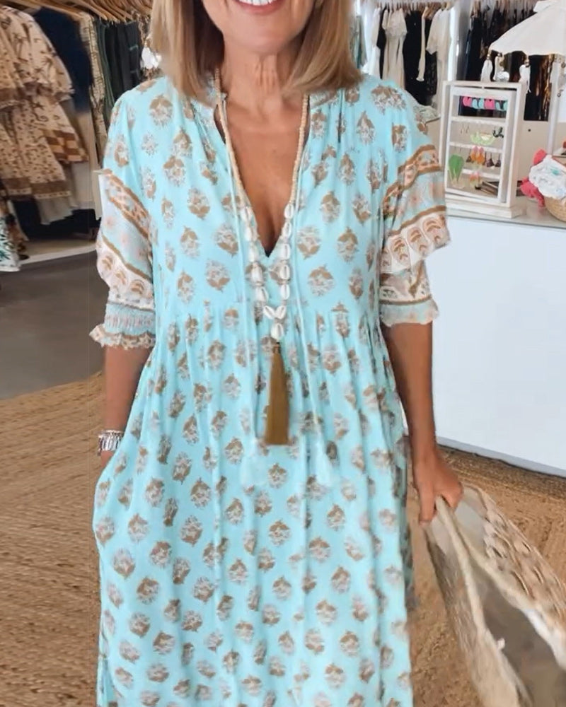 A woman wearing the Crystal boho beach dress with a flowing skirt, walking along the seaside.