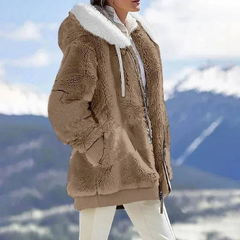 A woman wearing a plush oversized hooded zip jacket in blue and cream colour-block panels.