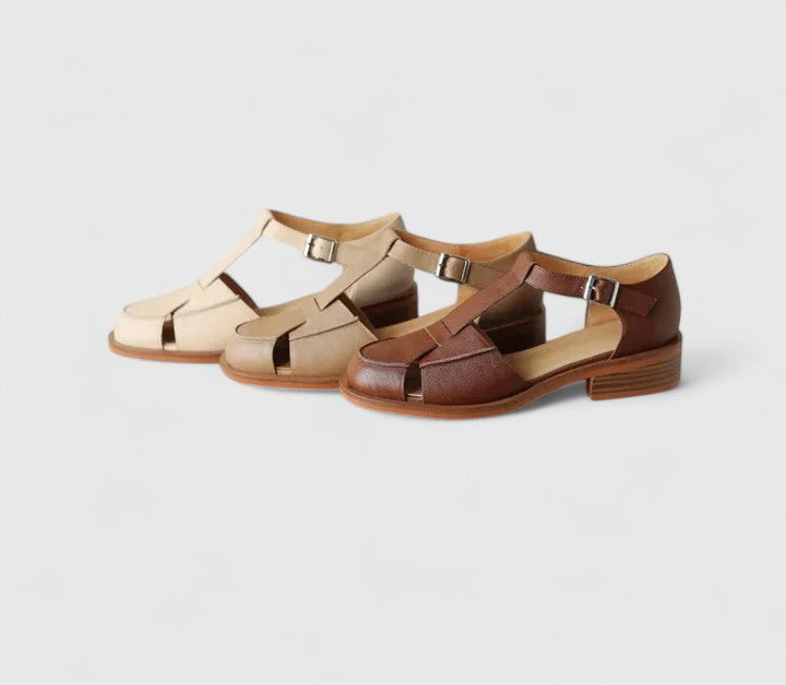 Woman wearing beige strapped Mary Jane sandals on a sunny terrace.