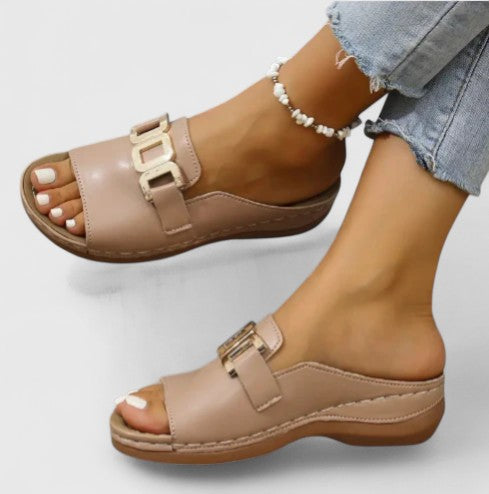 A woman wearing white comfort slides with a golden front trim and a cushioned sole.