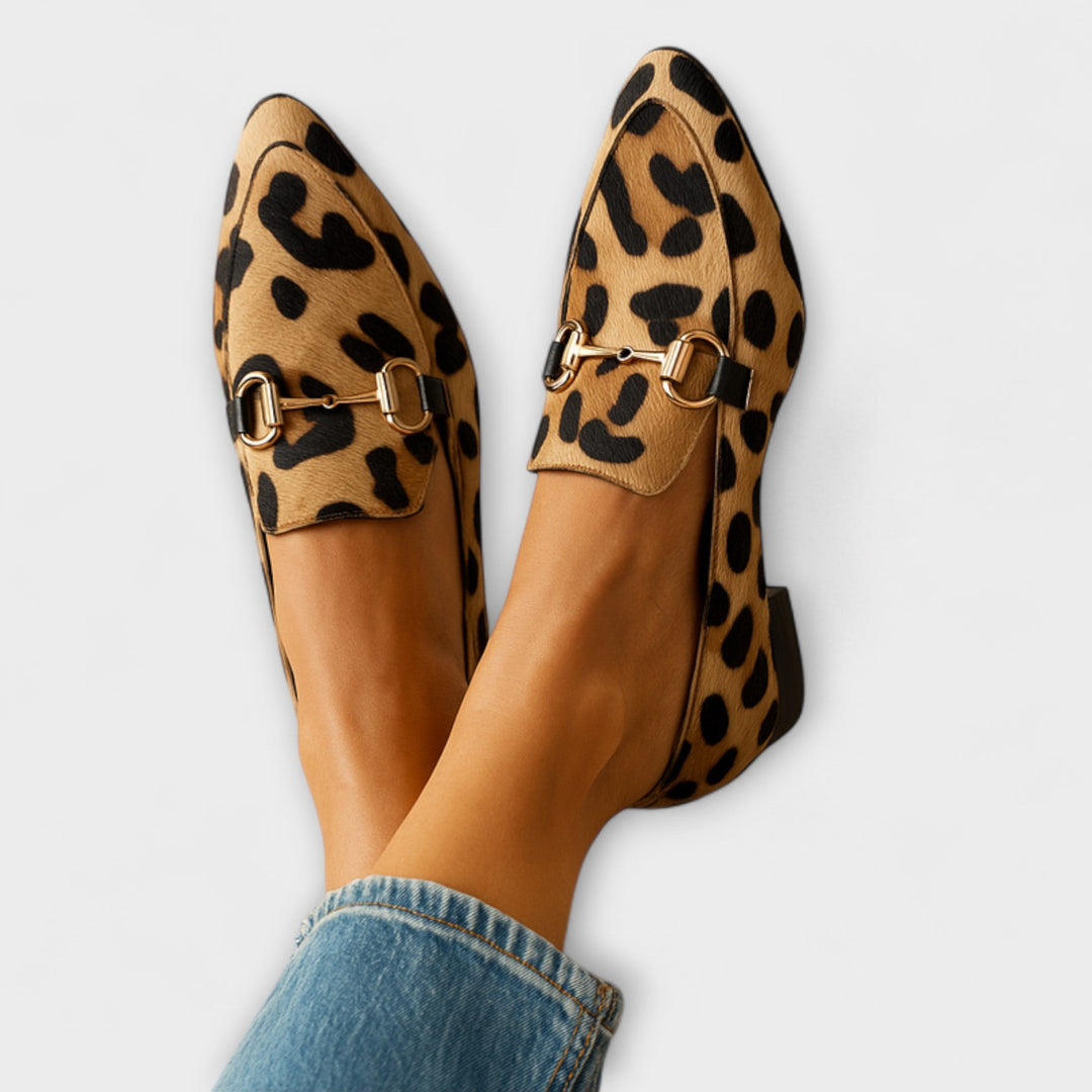 A woman wearing leopard-print loafers with a gold horsebit detail and a smart outfit