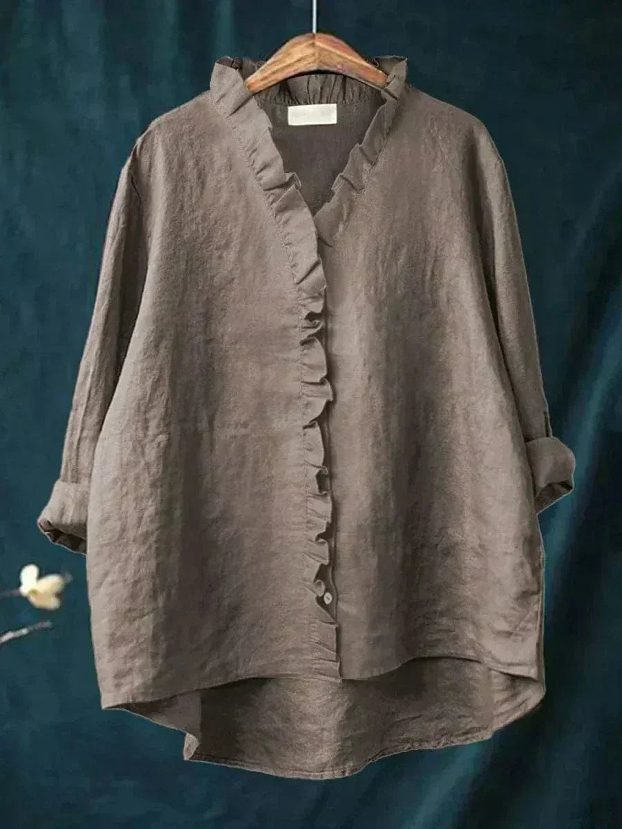 Woman wearing a plain ruffle-front summer blouse with a soft, flowing silhouette.