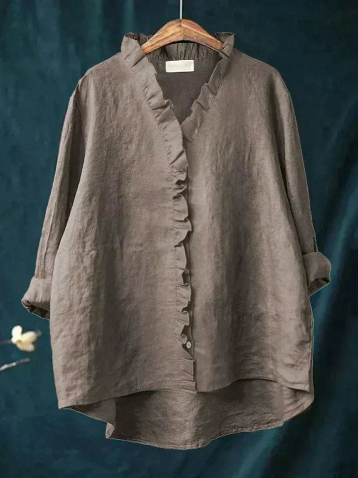 Woman wearing a plain ruffle-front summer blouse with a soft, flowing silhouette.