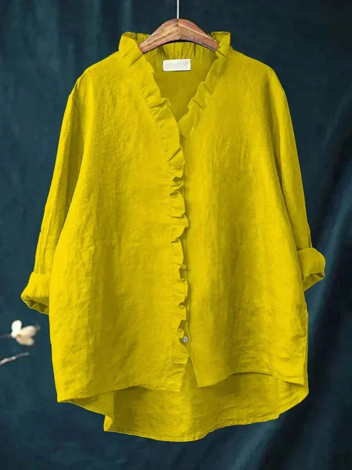 Woman wearing a plain ruffle-front summer blouse with a soft, flowing silhouette.