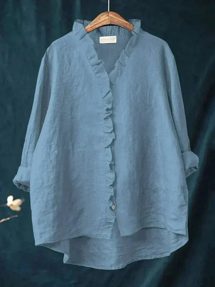 Woman wearing a plain ruffle-front summer blouse with a soft, flowing silhouette.