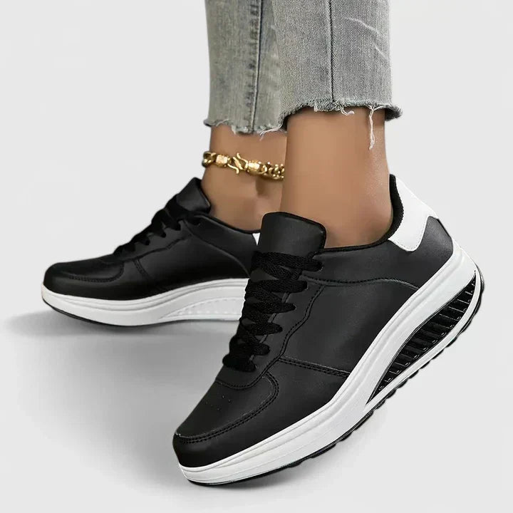 A woman walking comfortably in black and white lace-up orthopaedic support shoes.