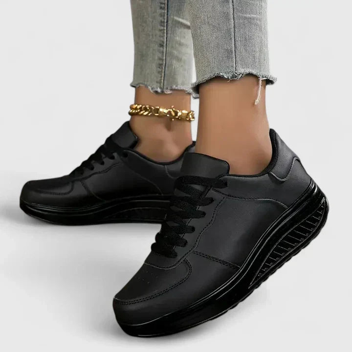 A woman walking comfortably in black and white lace-up orthopaedic support shoes.