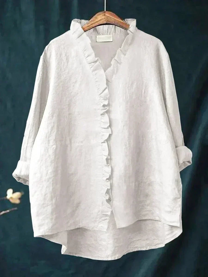 Woman wearing a plain ruffle-front summer blouse with a soft, flowing silhouette.
