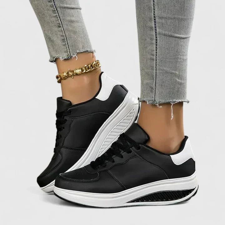 A woman walking comfortably in black and white lace-up orthopaedic support shoes.