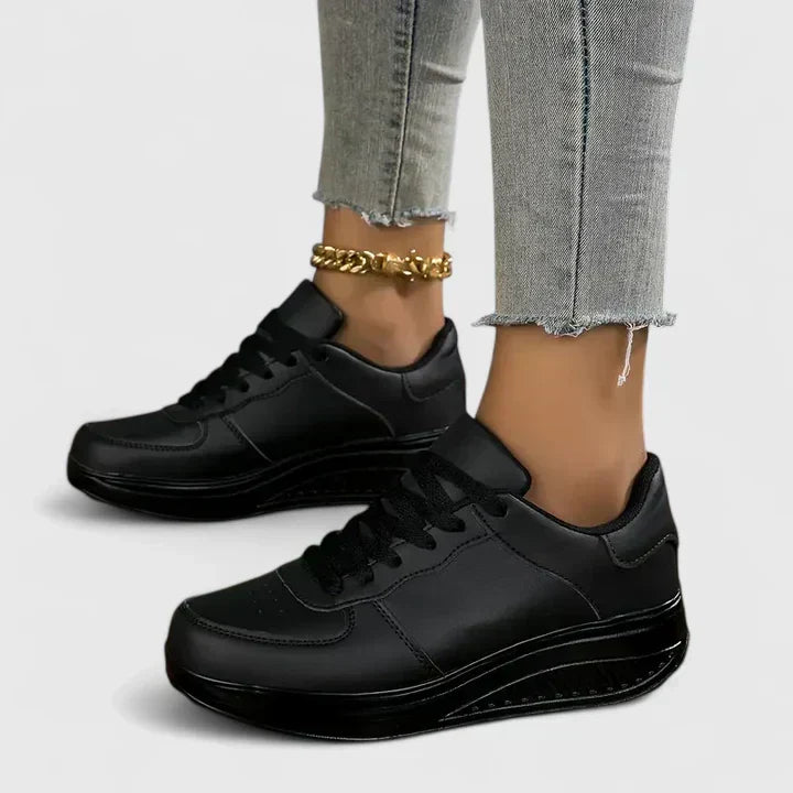 A woman walking comfortably in black and white lace-up orthopaedic support shoes.