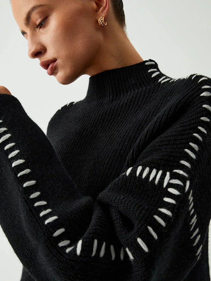 A woman wearing an oversized mock-neck sweater with whipstitch detailing, cosy and stylish.