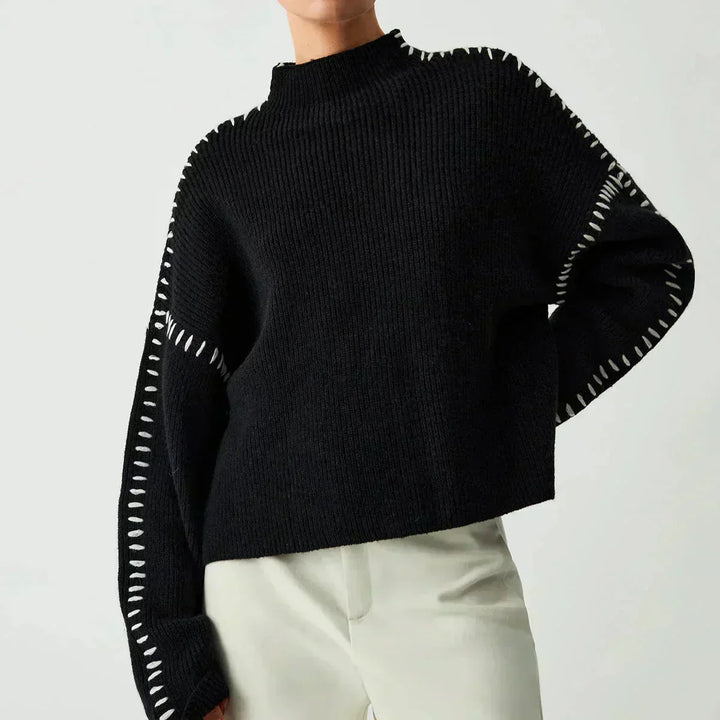 A woman wearing an oversized mock-neck sweater with whipstitch detailing, cosy and stylish.