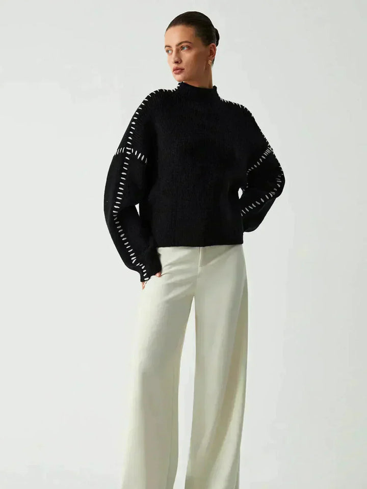 A woman wearing an oversized mock-neck sweater with whipstitch detailing, cosy and stylish.