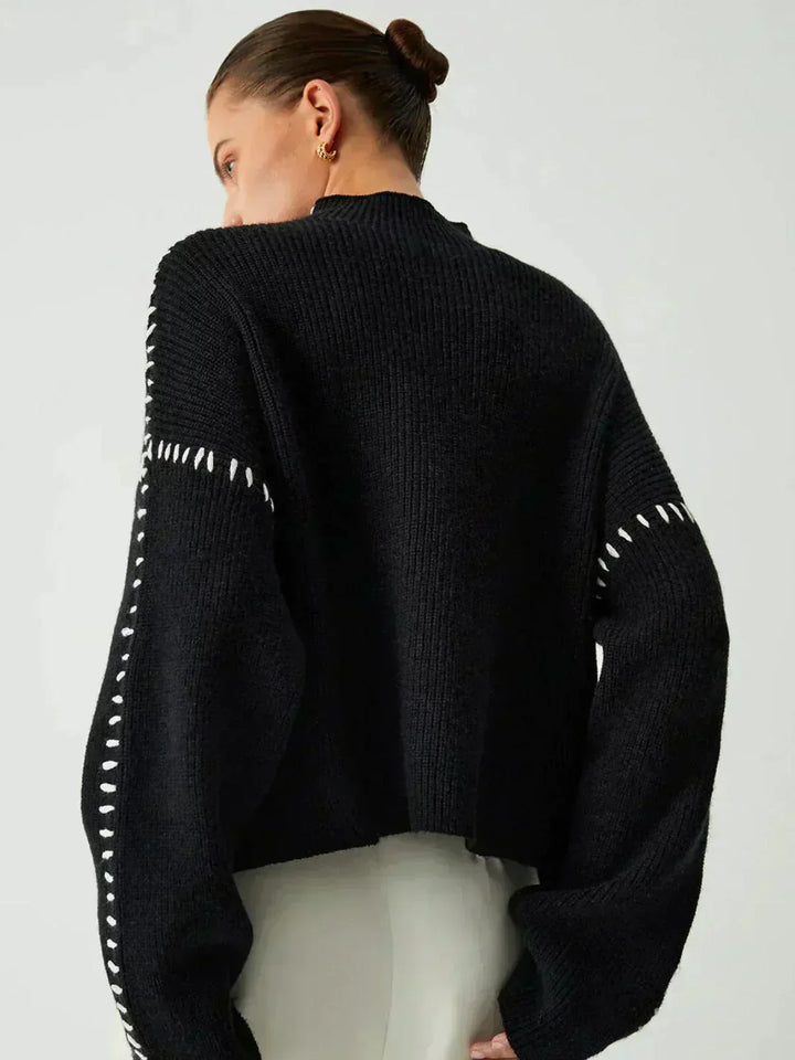 A woman wearing an oversized mock-neck sweater with whipstitch detailing, cosy and stylish.