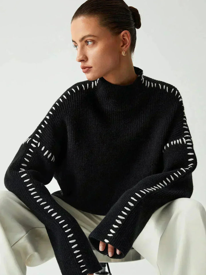 A woman wearing an oversized mock-neck sweater with whipstitch detailing, cosy and stylish.