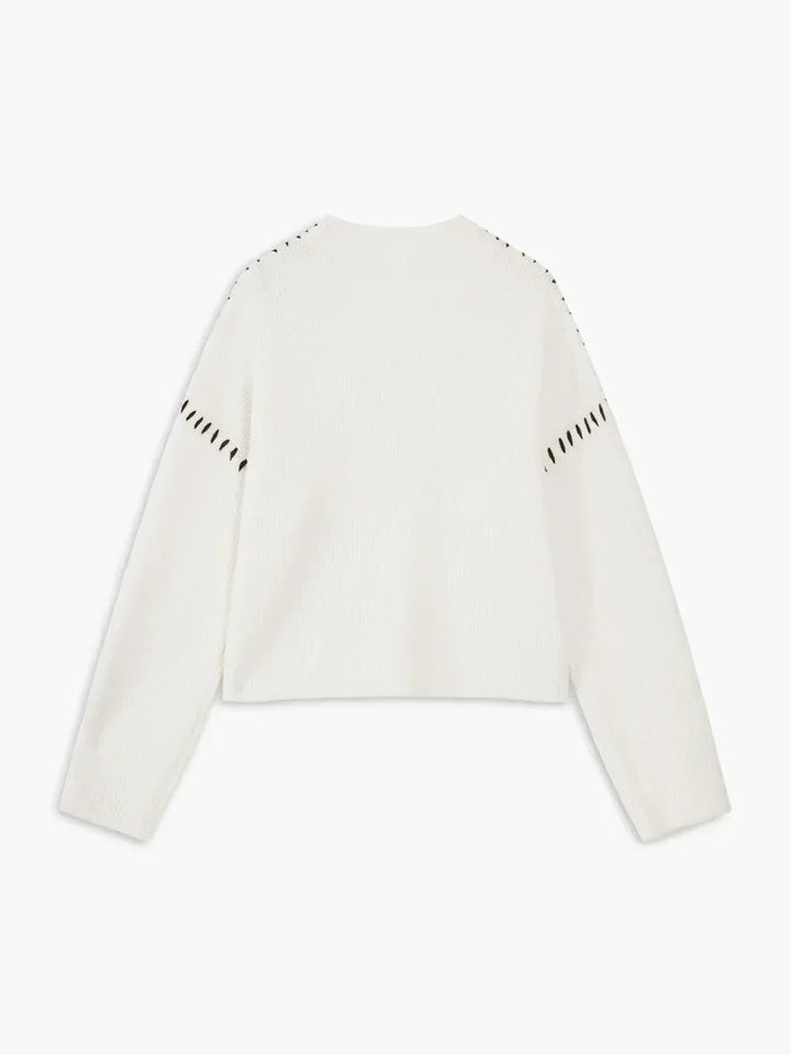 A woman wearing an oversized mock-neck sweater with whipstitch detailing, cosy and stylish.