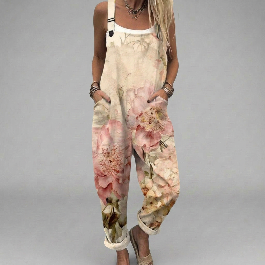 Woman wearing cream overalls covered in soft pink and peach watercolour flowers, styled with sandals.
