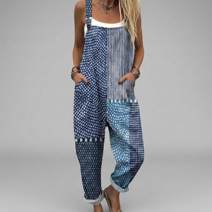 Woman wearing deep blue overalls with a boho patchwork print of dots, stripes and ornaments.