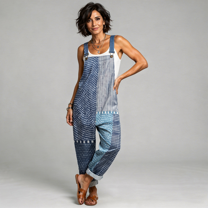 Woman wearing deep blue overalls with a boho patchwork print of dots, stripes and ornaments.