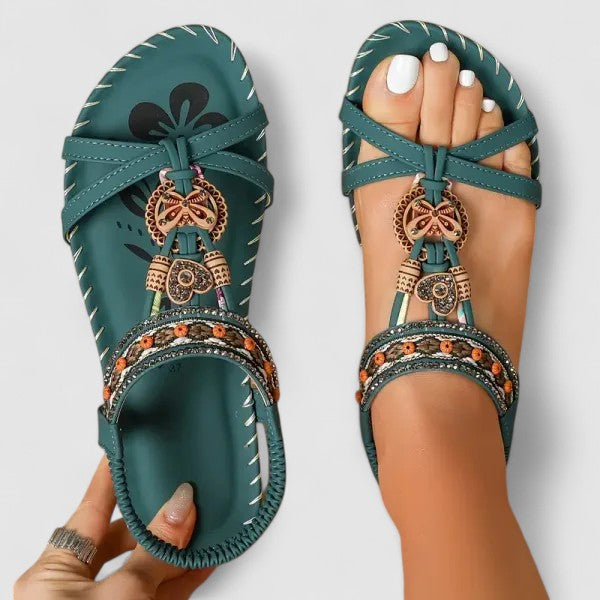 A woman wearing black beaded boho sandals with braided straps, a golden medallion and a stretchy slingback.