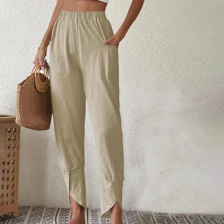 Woman wearing tapered pants with a slit hem at the ankle, walking near the coast.