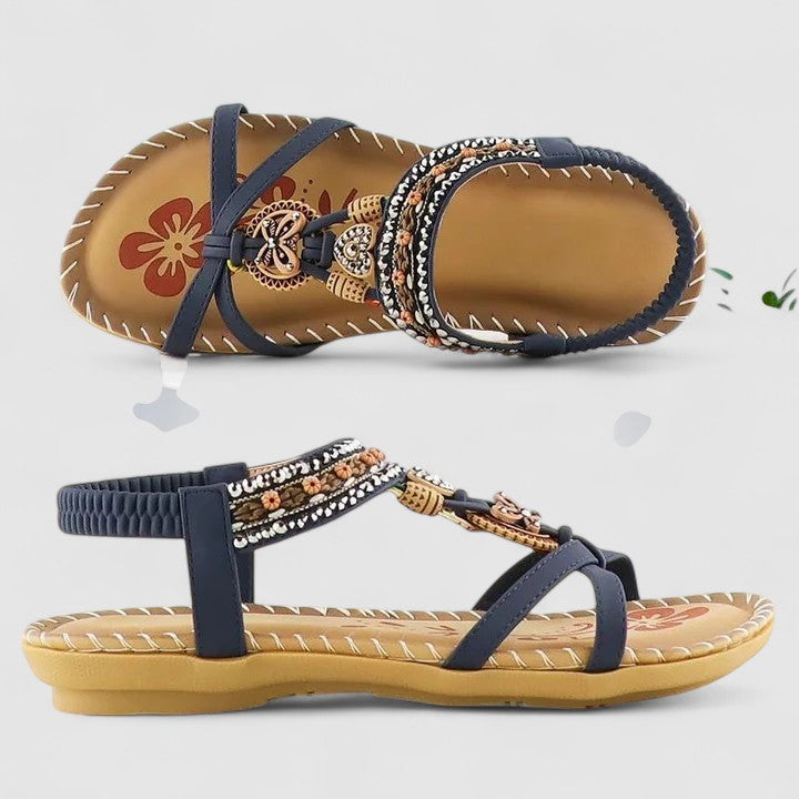 A woman wearing black beaded boho sandals with braided straps, a golden medallion and a stretchy slingback.