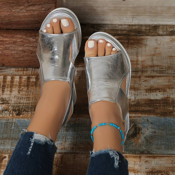 A woman wearing gold metallic sandals with a cushioned insole and wide, supportive fit.
