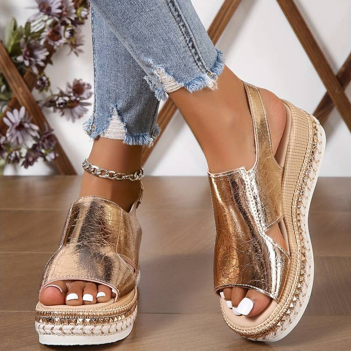 A woman wearing gold metallic sandals with a cushioned insole and wide, supportive fit.