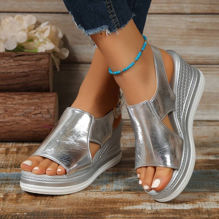 A woman wearing gold metallic sandals with a cushioned insole and wide, supportive fit.