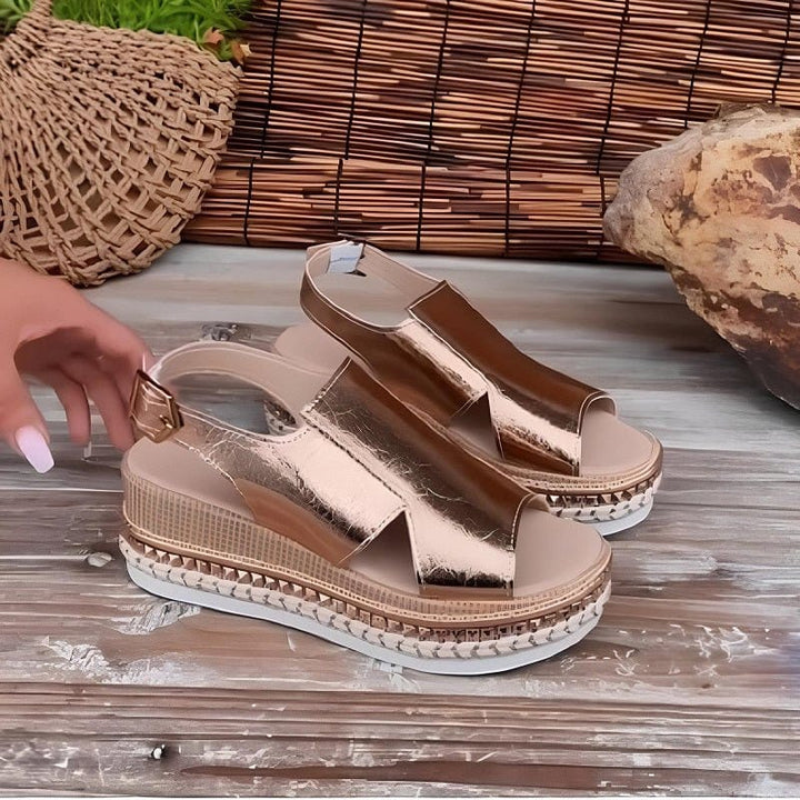 A woman wearing gold metallic sandals with a cushioned insole and wide, supportive fit.