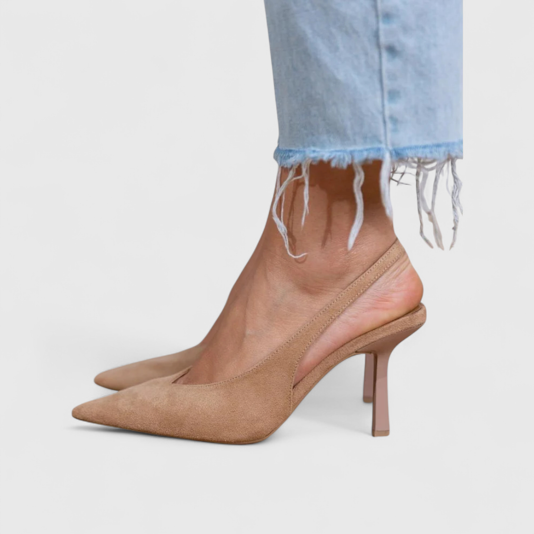 A woman wearing beige pointed slingback stilettos with a slim high heel.