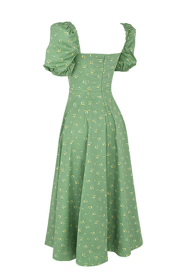 A woman wearing a floral midi dress with puff sleeves and a tie-front bodice, standing in the sunshine.