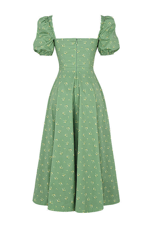 A woman wearing a floral midi dress with puff sleeves and a tie-front bodice, standing in the sunshine.