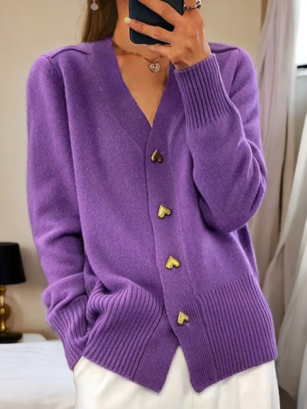 A woman wearing a soft V-neck button cardigan, elegant and cosy layered over a top.