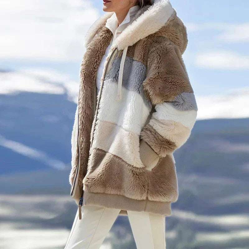 A woman wearing a plush oversized hooded zip jacket in blue and cream colour-block panels.