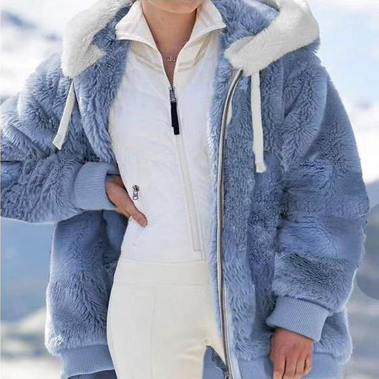 A woman wearing a plush oversized hooded zip jacket in blue and cream colour-block panels.