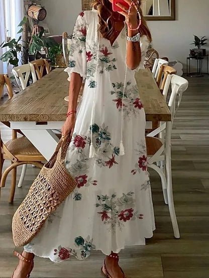 A woman wearing the Margaret boho midi dress with tassel ties at the neckline and a ruffled skirt.