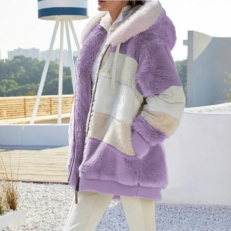 A woman wearing a plush oversized hooded zip jacket in blue and cream colour-block panels.
