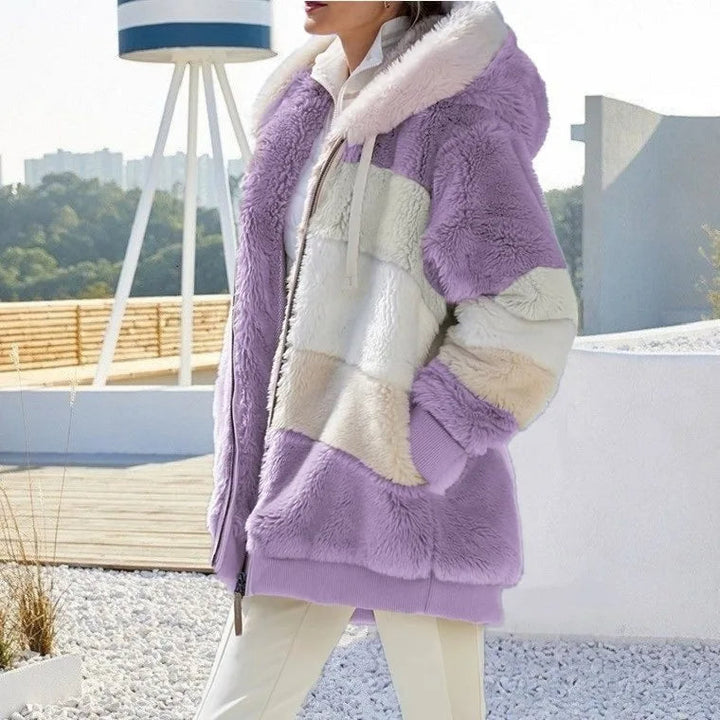 A woman wearing a plush oversized hooded zip jacket in blue and cream colour-block panels.