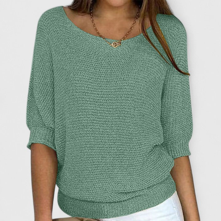 A woman wearing a soft purple sweater with a wide neckline and gently shaped fit.