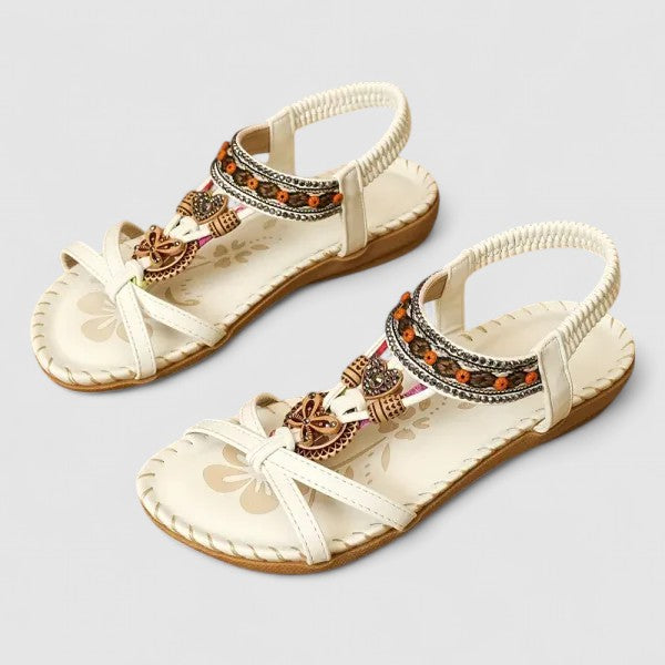 A woman wearing black beaded boho sandals with braided straps, a golden medallion and a stretchy slingback.