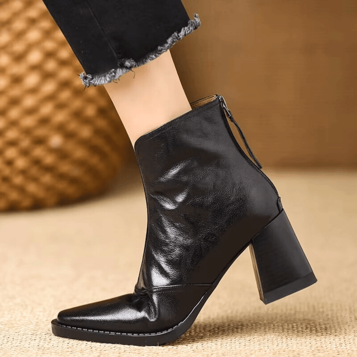 A woman in tailored pants wearing polished mid-heel ankle boots with a back zip.