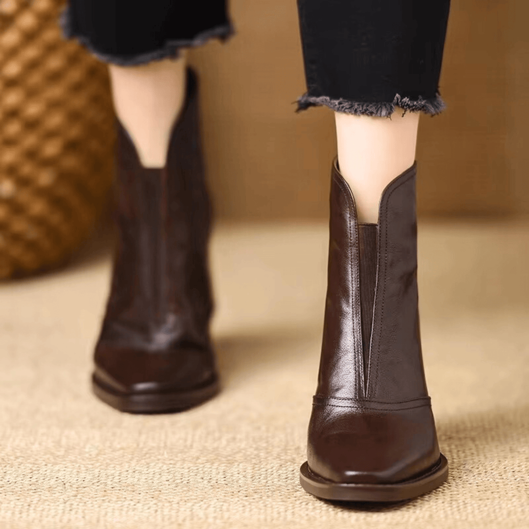 A woman in tailored pants wearing polished mid-heel ankle boots with a back zip.